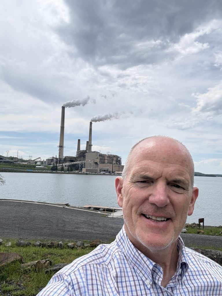 Matt standing in front of a power plant from a distance